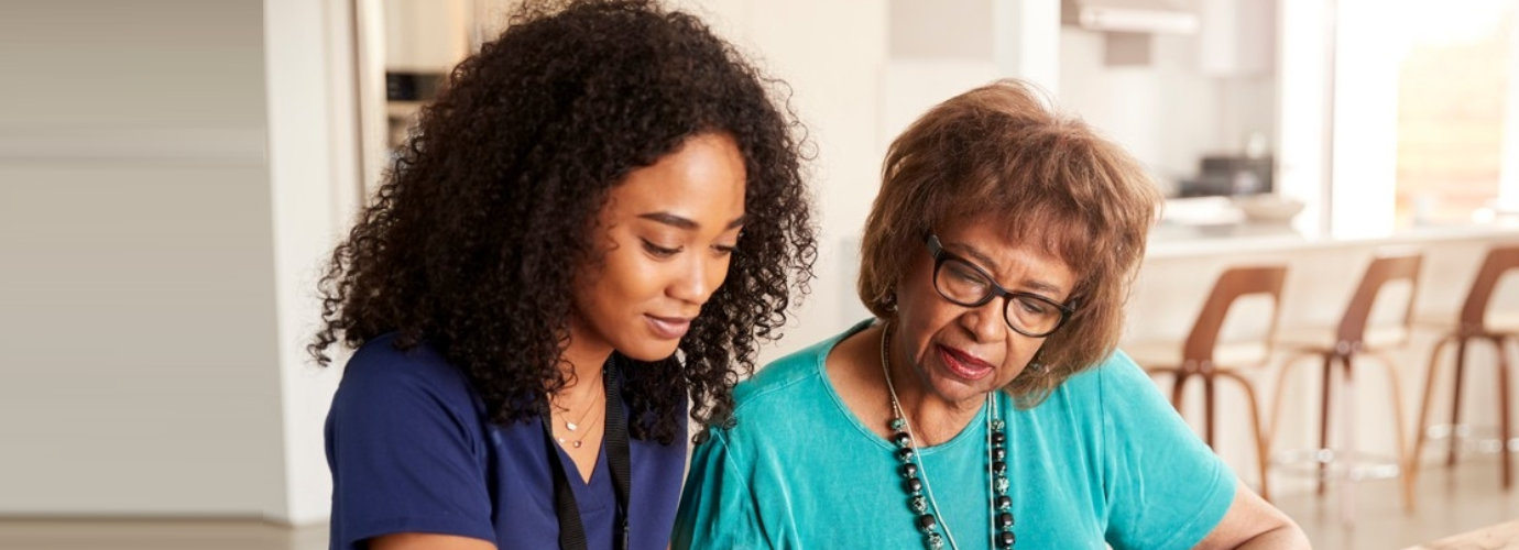 senior woman assisted by caregiver writing