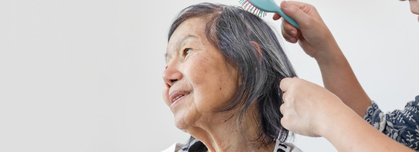 a person combing the hair of senior woman